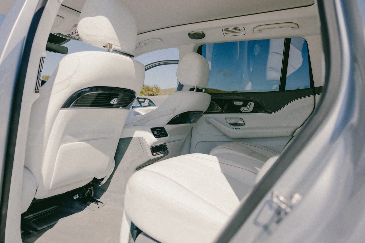 Mercedes-Maybach GLS rear executive cabin — reclining white-leather rear seats and fold-out console, seen through the open rear door