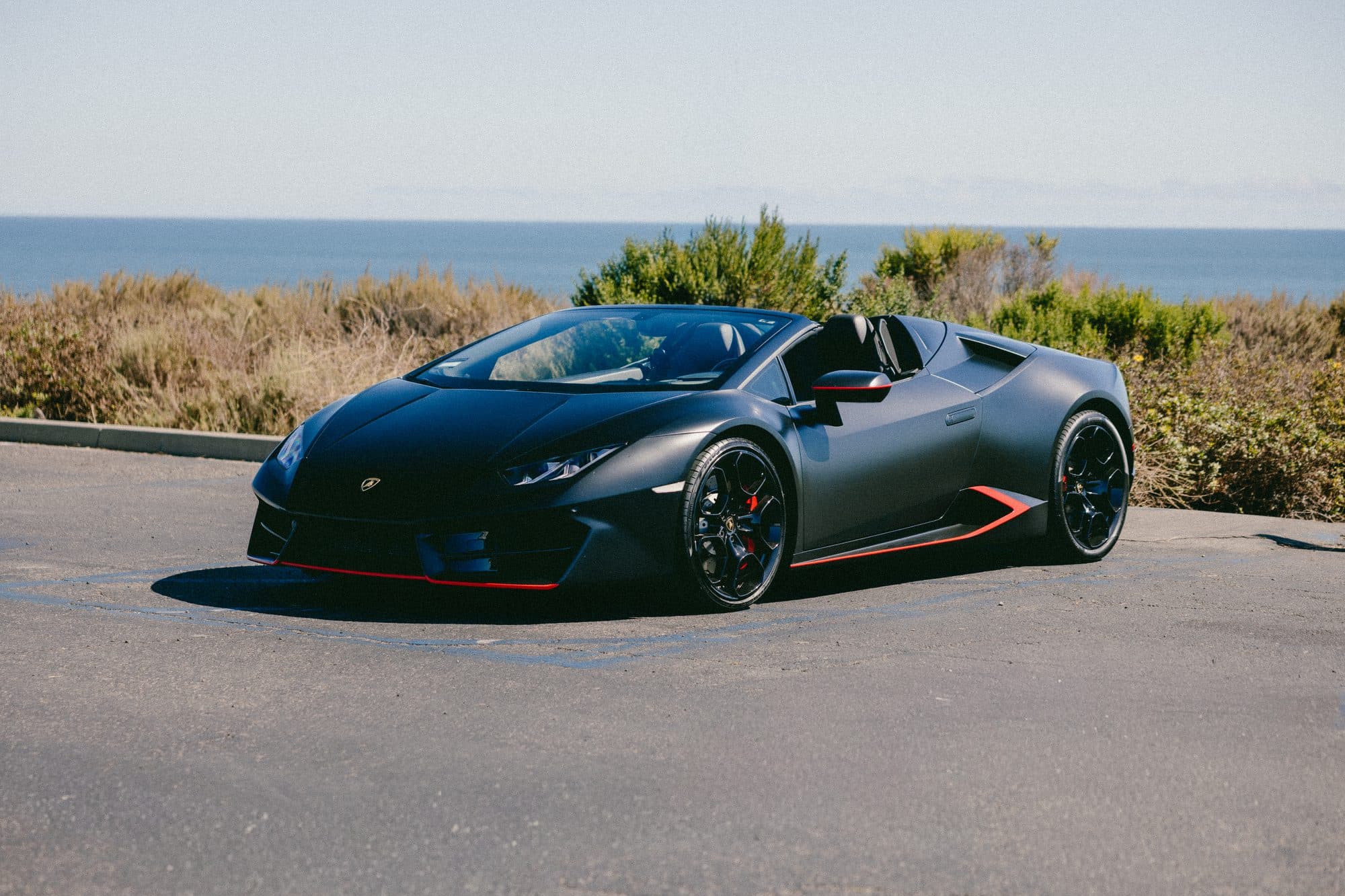 Matte-black Lamborghini Huracán EVO Spyder, top down above the ocean