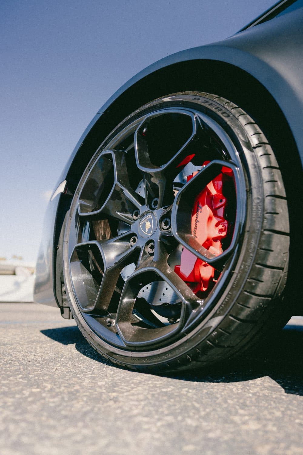 Close-up of the Huracán front wheel: black multi-spoke alloy with a red brake caliper and Pirelli tire